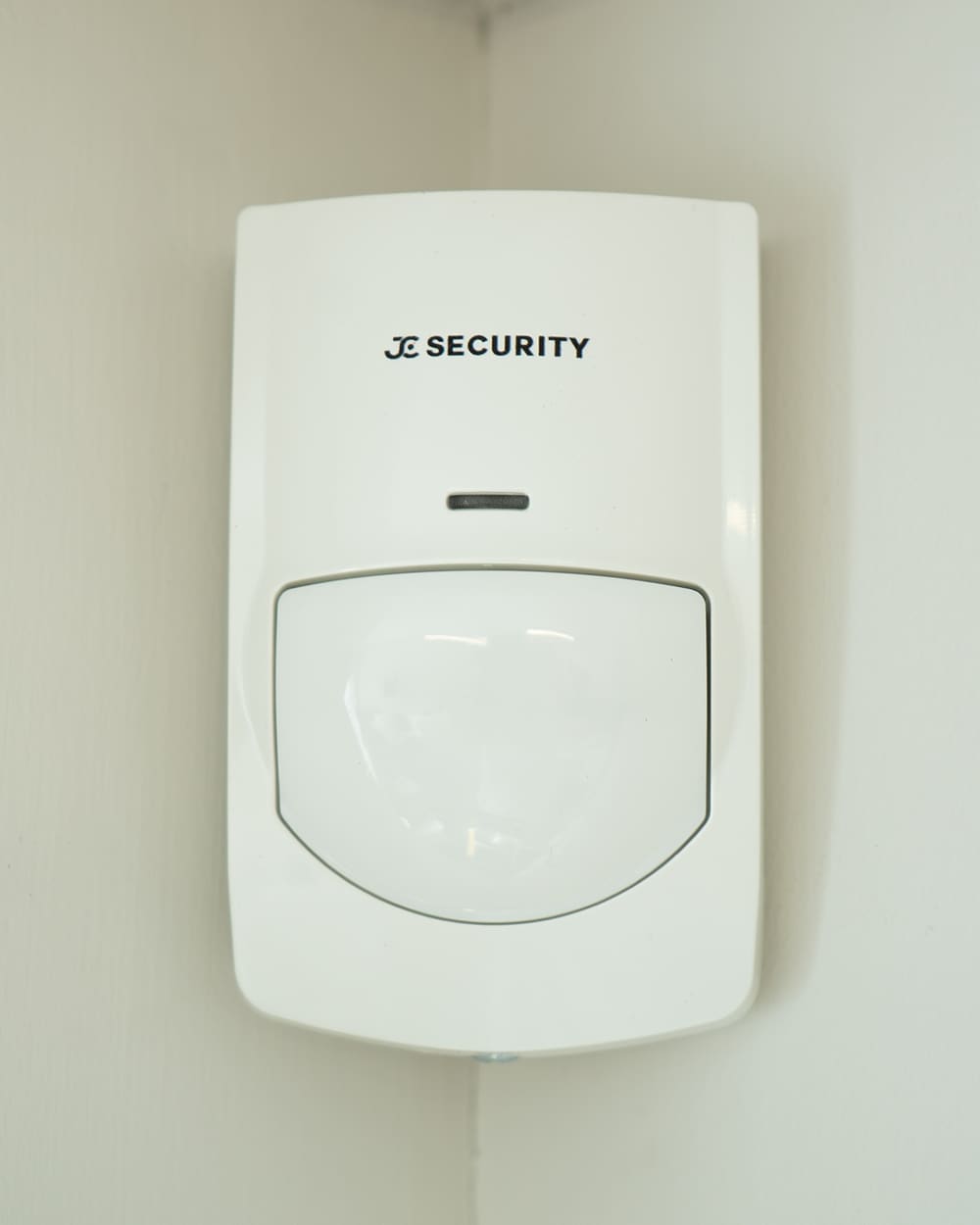 JC Security branded motion sensor installed in a room corner